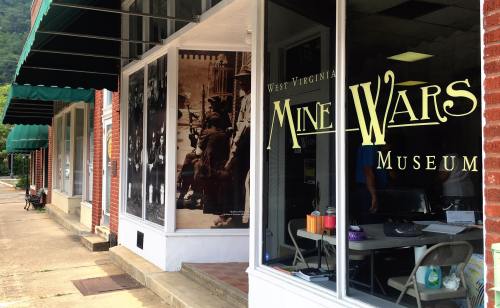 Exterior of the West Virginia Mine Wars Museum, featuring large windows and a historical photo display.