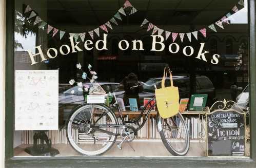 A bookstore window display featuring a bicycle, colorful books, and a sign for writing workshops.