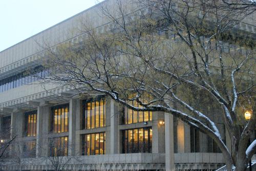 A modern building with large windows, surrounded by bare trees and light snow, creating a wintry atmosphere.