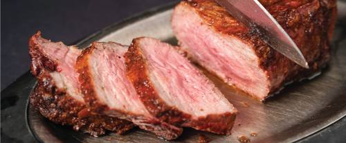 Sliced juicy steak on a metal platter, showcasing a perfectly cooked pink interior.