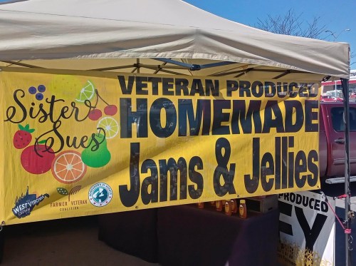 A colorful banner at a market stall reads "Veteran Produced Homemade Jams & Jellies" with fruit graphics.