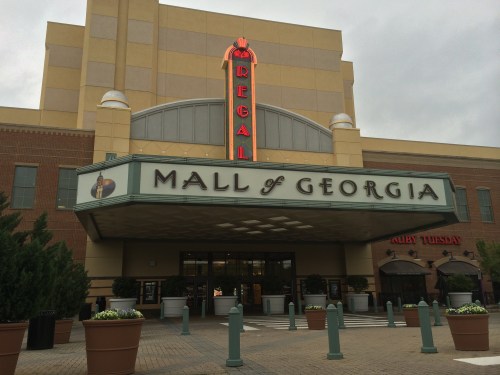Entrance of the Mall of Georgia featuring a Regal cinema sign and Ruby Tuesday restaurant, under a cloudy sky.