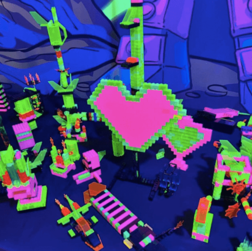 Colorful pixel art structures in neon green and pink, including a large heart, set against a vibrant background.