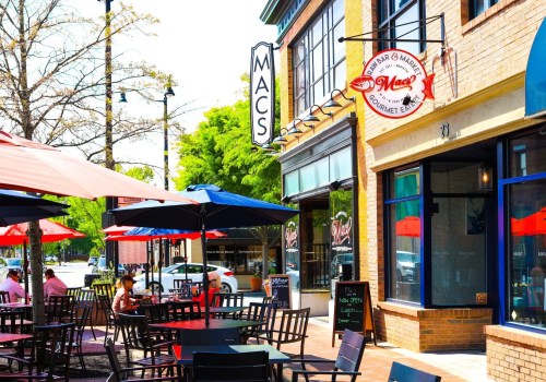 Outdoor dining area with colorful umbrellas at Mac's Gourmet Eatery, featuring tables and a vibrant storefront.
