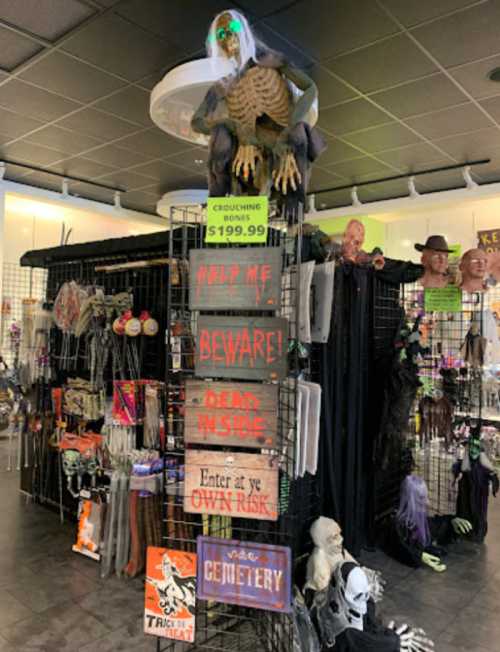 A spooky display in a store featuring skeletons, signs, and Halloween decorations.