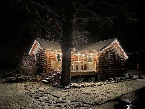 A cozy log cabin illuminated with festive lights, surrounded by snow at night.