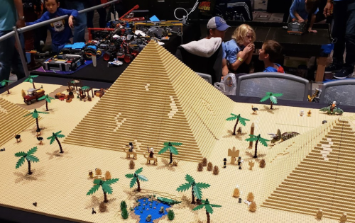 A detailed LEGO scene featuring pyramids, palm trees, and a desert landscape with people in the background.