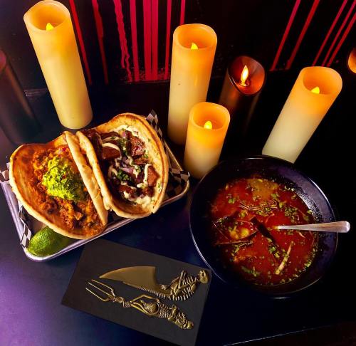 A plate with tacos, a bowl of soup, and candles, creating a cozy, atmospheric dining scene.