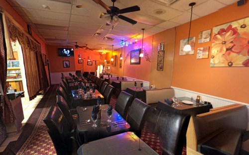 Cozy restaurant interior with dark seating, colorful artwork, and soft lighting, creating an inviting atmosphere.