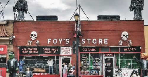 A Halloween store with spooky decorations, including skeletons and masks, showcasing costumes and party supplies.