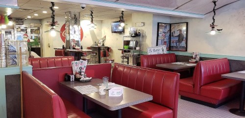 Cozy diner interior with red booths, tables set for dining, and a casual atmosphere.