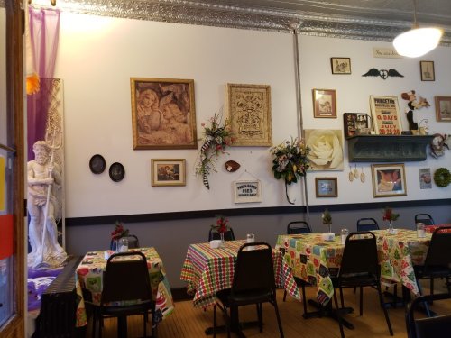 Cozy restaurant interior with checkered tablecloths, framed art, and decorative flowers on the walls.