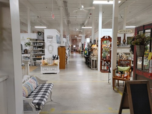A spacious antique store aisle filled with various vintage items, furniture, and decor on display.