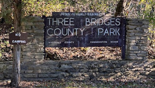 Sign for Three Bridges County Park, featuring stone structure and a "No Camping" notice nearby.
