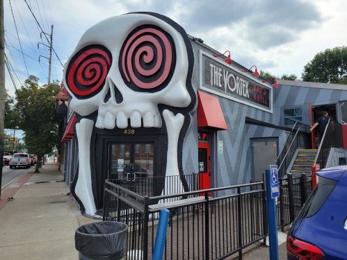 A quirky restaurant exterior featuring a large skull design with spiral eyes, named "The Vortex."