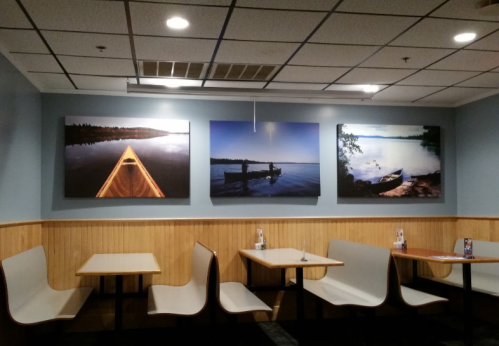 A cozy restaurant interior featuring wooden booths and three large nature-themed photographs on the wall.