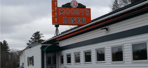 Sign for Moody's Diner on a cloudy day, featuring a classic diner exterior with white siding and green awning.