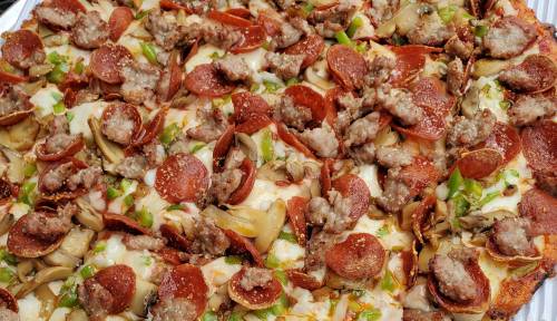A close-up of a pizza topped with pepperoni, sausage, green peppers, and mushrooms on a cheesy crust.