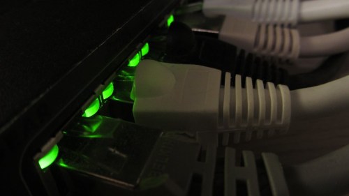 Close-up of network cables connected to a router, with green indicator lights glowing.