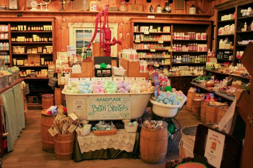A cozy shop filled with colorful bath products, including handmade bath bombs, displayed in vintage tubs and shelves.