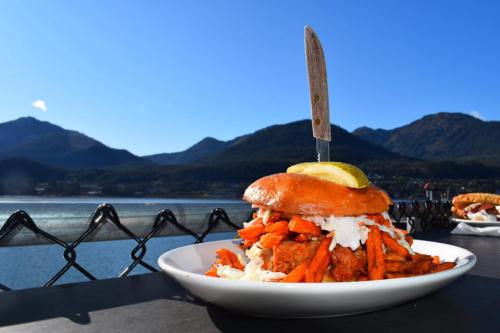 A towering burger topped with fries and a slice of lime, set against a scenic mountain backdrop.