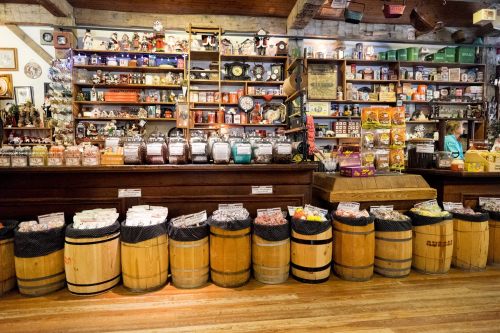 A colorful candy shop interior with shelves of sweets, jars, and barrels filled with various candies.