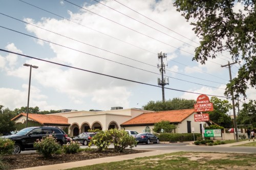 A restaurant with a red tile roof and a sign for "King Ranch Mexican Food," surrounded by cars and greenery.