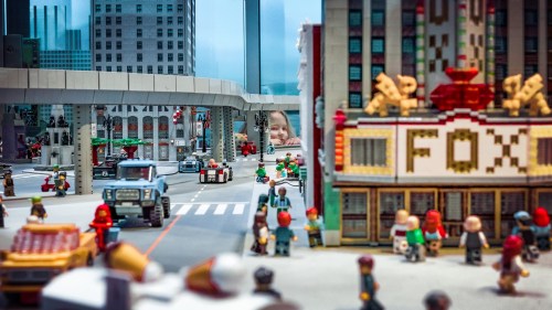 A vibrant LEGO city scene with buildings, vehicles, and mini-figures bustling on the streets.