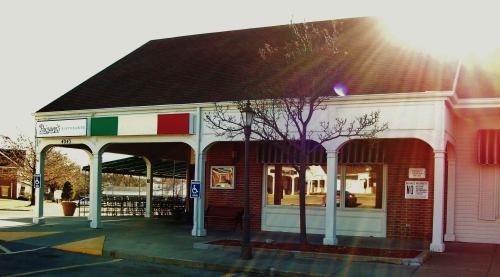 Exterior of a restaurant with a peaked roof, green and red accents, and a sunny atmosphere. Accessible parking visible.