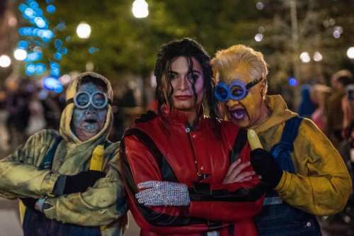 Three people in costume: one as Michael Jackson and two as Minions, posing together in a festive outdoor setting.