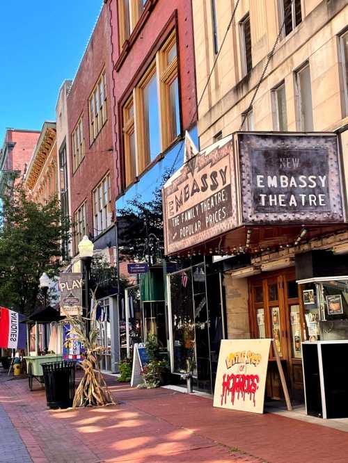 A vibrant street scene featuring the Embassy Theatre with a marquee and colorful storefronts in a lively urban setting.