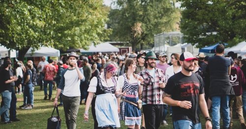 A lively outdoor festival scene with people in various outfits enjoying the event among tents and trees.