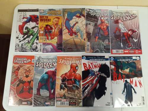 A collection of comic books featuring Spider-Man and Batman, displayed on a table.