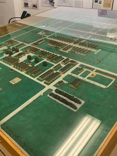 A detailed model of a historical site, featuring buildings, roads, and green spaces under a glass display.