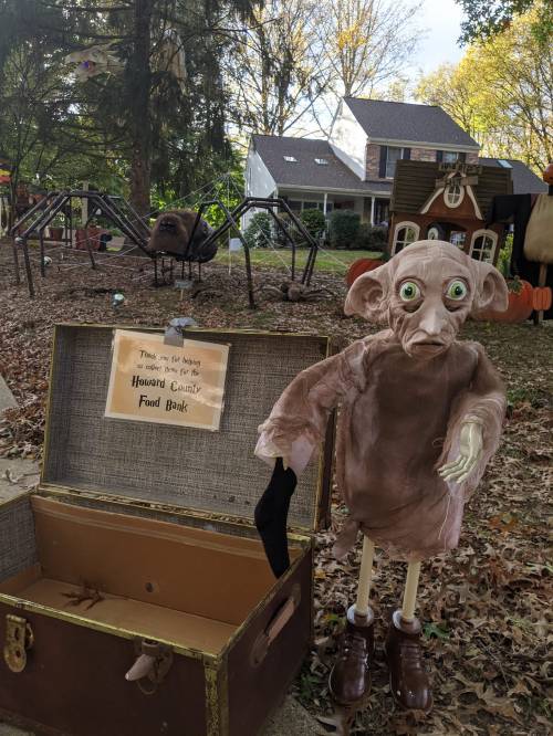 A spooky yard display features a creepy figure next to a treasure chest labeled "Howard County Food Bank."