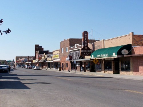 A sunny street view of a small town with vintage storefronts and a clear blue sky.