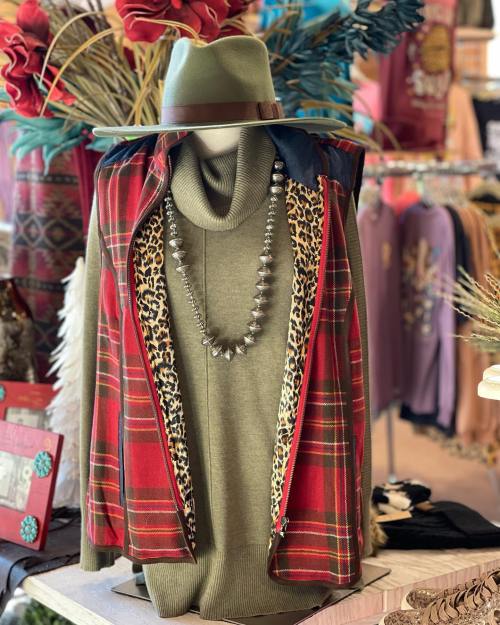 A stylish display featuring a green sweater, plaid vest, and leopard print lining, accessorized with a statement necklace.