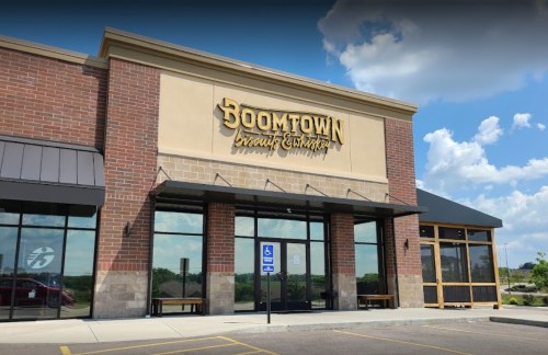 Exterior of Boomtown Brewery with large signage, glass doors, and a clear blue sky in the background.