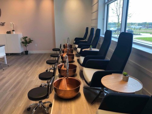 A modern nail salon interior featuring pedicure chairs, copper basins, and a clean, bright atmosphere.