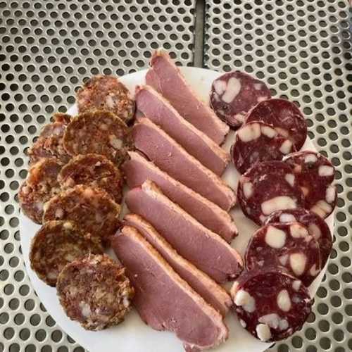 A plate of assorted meats, including sliced ham, sausage patties, and circular slices of salami.