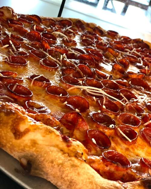 A close-up of a pepperoni pizza with a golden crust and melted cheese, topped with slices of pepperoni and shredded cheese.