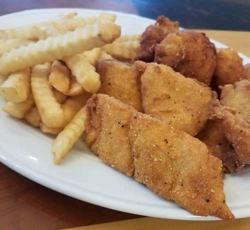 A plate of crispy fried fish, hush puppies, and crinkle-cut fries.