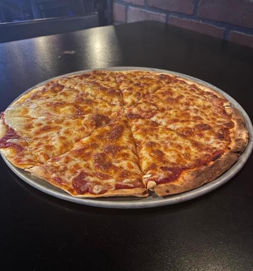 A round pizza with melted cheese and pepperoni, sliced into eight pieces, on a metal tray against a dark background.
