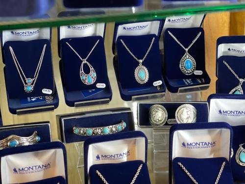 Display of silver jewelry featuring turquoise stones, arranged in blue velvet boxes with price tags.