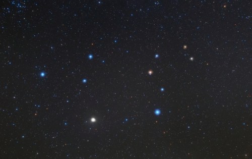 A starry night sky filled with numerous bright stars and distant celestial objects against a dark background.