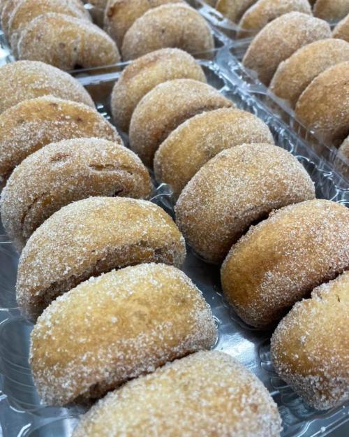 A close-up of sugar-coated pastries arranged in a tray, showcasing their golden-brown color and soft texture.