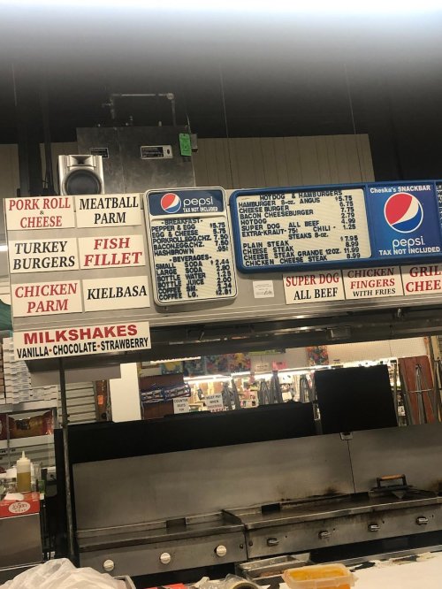 Menu board displaying various food items like burgers, fish, chicken, and milkshakes at a diner or snack bar.