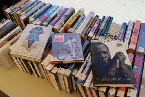 A table covered with stacks of books, featuring three prominent titles on top.