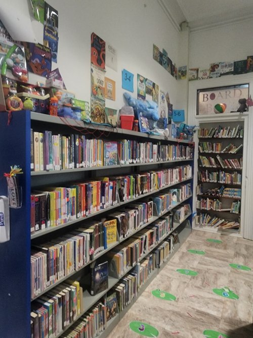 A colorful library corner with bookshelves filled with books and decorations, including toys and posters on the walls.