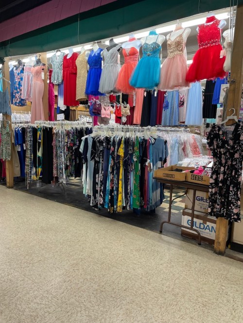 A clothing store display featuring a variety of dresses and outfits hanging on racks under bright lights.